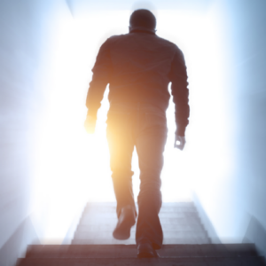silhouette of man walking into a light bathed door