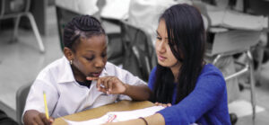 tutor helping student at a small desk